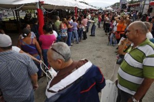 People stand in line to buy food at a state-run street market in Caracas