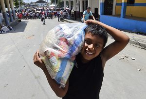 A boy smiles after receiving food supplies in Manta, Ecuador on April 20, 2016.  The death toll from Ecuador's earthquake was set to rise sharply after authorities warned that 1,700 people were still missing and anger gripped families of victims trapped in the rubble. A 6.1-magnitude earthquake struck off the coast of Ecuador Wednesday, sowing new panic four days after a more powerful quake killed more than 525 people, with hundreds still missing. / AFP PHOTO / LUIS ACOSTA -----